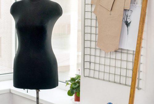 workplace with sewing equipment, fabrics, patterns, sewing studio with dummy and clothes hangers, couturier